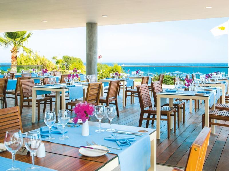 Offenes Restaurant mit Holzmöbeln und Blick auf das Meer bei Tageslicht.