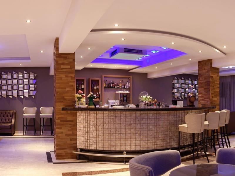 Moderner Hotelbarbereich mit elegantem Tresen, bequemen Sitzmöglichkeiten und stimmungsvoller Beleuchtung.