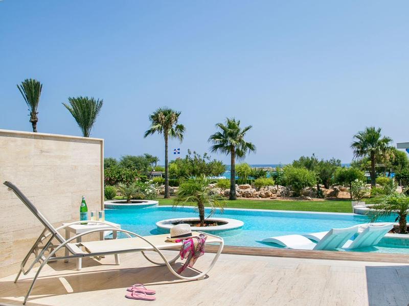 Moderner Außenbereich mit Pool, Liegestühlen, Palmen und Whirlpool bei klarem Himmel.