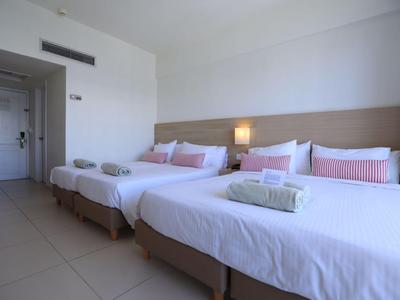 Camera d'hotel con due letti grandi, lenzuola bianche e cuscini rosa.