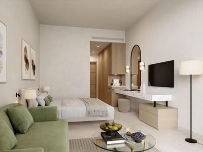 Moderne hotelkamer met groene bank, tweepersoonsbed, tv en lichte inrichting.