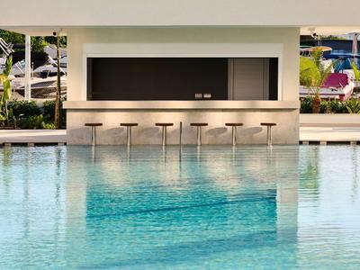 Piscina moderna con area bar e sgabelli nella zona esterna di un hotel.