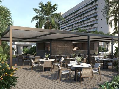 Moderner Außenbereich mit Tischen und Stühlen vor einem Hotel mit Palmen.