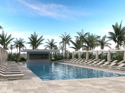 Modern buitenzwembad met ligstoelen en parasols omgeven door palmbomen onder een blauwe lucht.