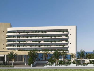 Modern hotelgebouw met balkons omgeven door palmbomen en een heldere blauwe lucht.