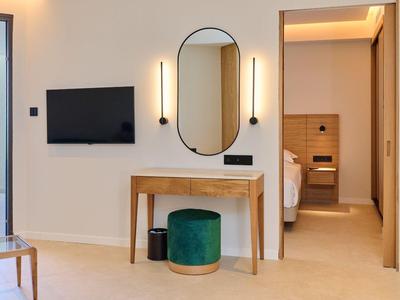 Camera d'hotel moderna con specchio, TV e vista sul bagno.