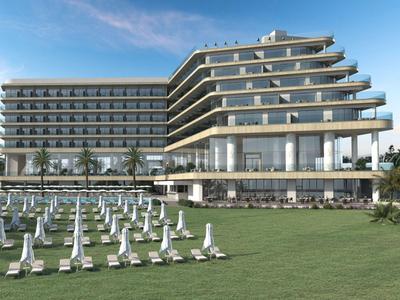 Modern hotel met meerdere verdiepingen en ligstoelen op een grasveld.