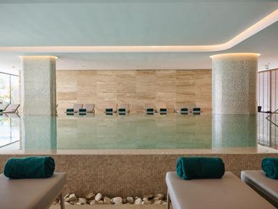 Piscina interna moderna con lettini e asciugamani turchesi in un hotel di lusso