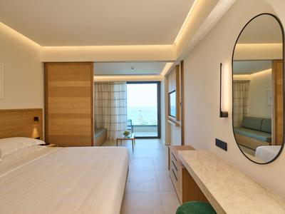 Camera d'hotel moderna con letto grande, dettagli in legno, specchio e vista sul mare e balcone.