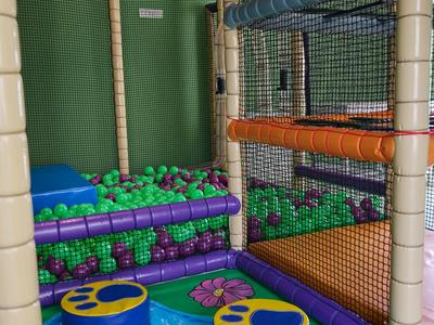 Parco giochi interno colorato con strutture da arrampicata, reti ed elementi morbidi, ideale per bambini in hotel.