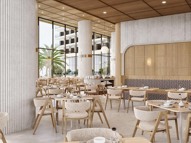 Licht, modern hotelrestaurant met houten meubels en grote ramen met uitzicht op palmbomen.