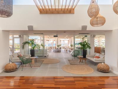 Hell eingerichteter Raum mit Holzboden, grünen Pflanzen und runden Teppichen, moderner Dekoration.