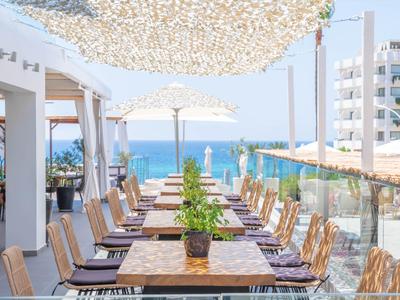 Terraza con mesas y sillas con vista al mar y sombrillas