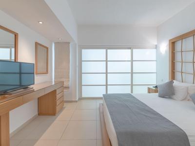 Helles, modernes Schlafzimmer mit großem Bett und Holzmöbeln in neutralen Farben.