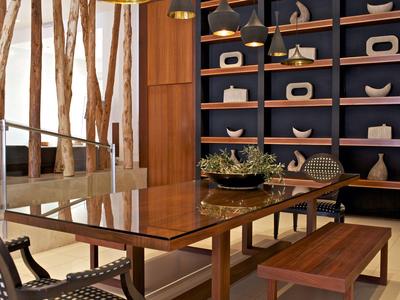 Área de comedor elegante con banco de madera, sillas y objetos decorativos en estantería