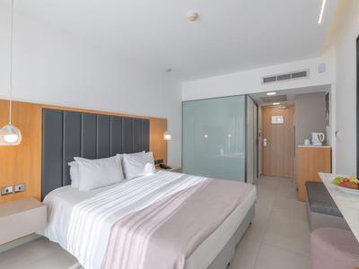 Modernes Hotelzimmer mit großem Bett, grauen Akzenten und hellem Holzmöbeln, heller Raumgestaltung.