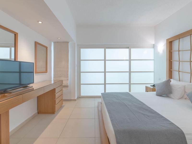 Helles, modernes Schlafzimmer mit großem Bett und Holzmöbeln in neutralen Farben.