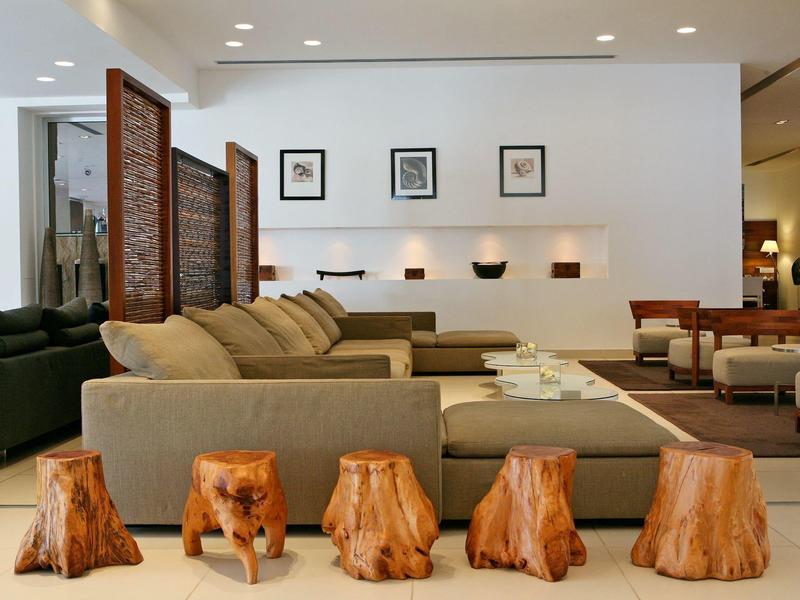 Modernes Wohnzimmer mit großen beigen Sofas, hölzernen Hockern und minimalistischer Wanddeko.