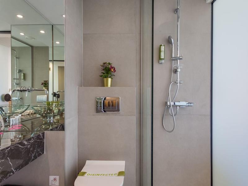 Moderne Badezimmerwand mit Toilette, Glas-Dusche und grauen Fliesen in schlichter Gestaltung.