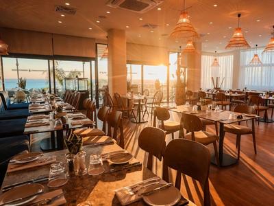 Stylová restaurace s výhledem na moře při západu slunce.