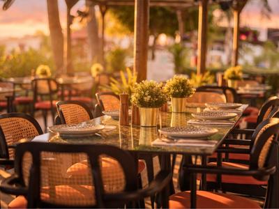 Elegantní stůl s prostřenými místy a květinovou dekorací v jasné otevřené restauraci.