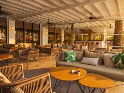 Pohodlná hotelová lounge s dřevěným a ratanovým nábytkem v teplém, tlumeném osvětlení.