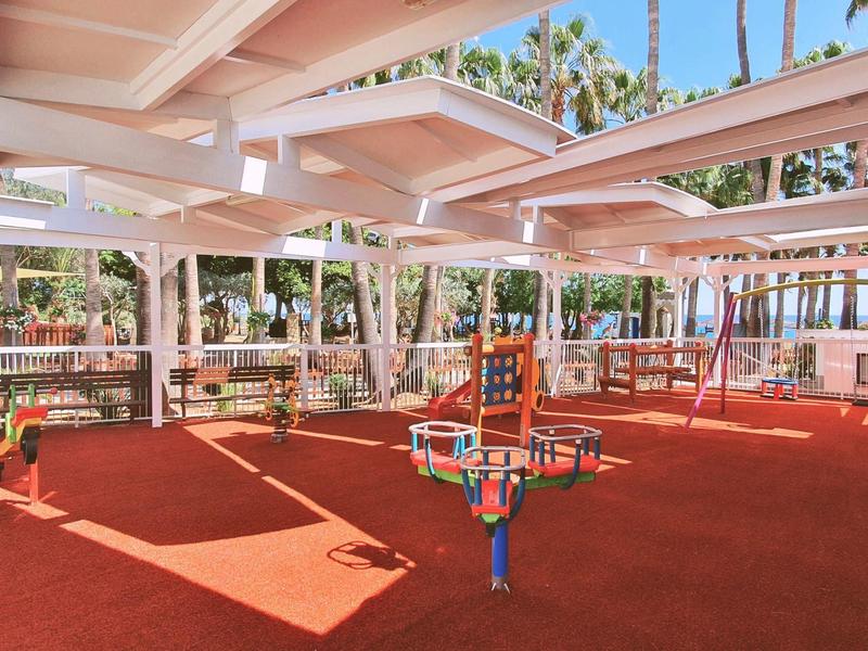 Aire de jeux couverte pour enfants avec équipements colorés et sol en caoutchouc rouge.