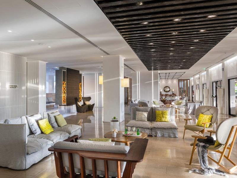 Espace lounge d'hôtel moderne avec canapés élégants, fauteuils et éclairage chaleureux.