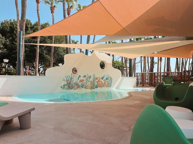 Piscine extérieure moderne avec voiles d'ombrage et sièges design en milieu tropical.