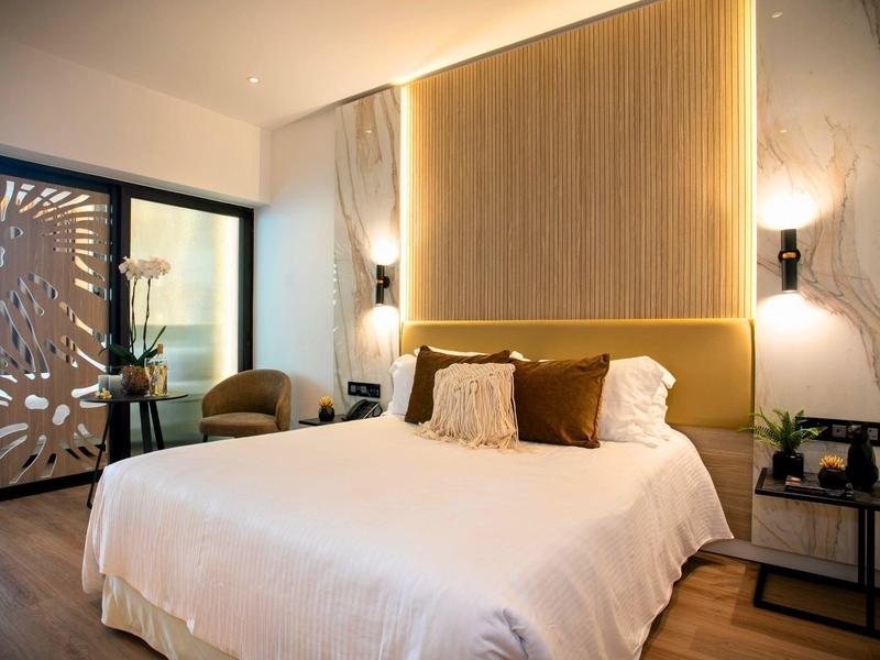 Chambre d'hôtel moderne avec grand lit et éclairage chaleureux.