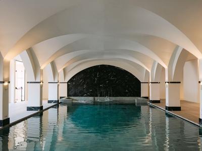 Innenpool mit weiß gewölbten Decken und sanfter Beleuchtung in einem Hotel.