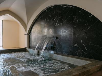 Moderner Innenpool mit Wasserfall und eleganten schwarzen Marmorwänden in einem Hotel.
