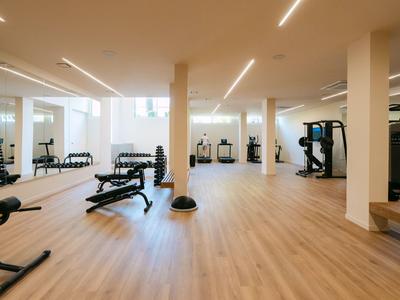 Großer, heller Fitnessraum mit modernen Geräten und Holzfußboden in einem Hotel.