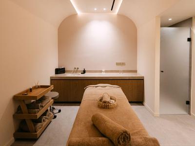 Ein ruhiger Massagebereich mit einem beigen Massagetisch und Handtüchern in einem modernen Raum.