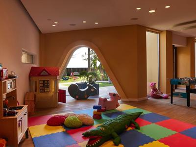 Kinderspielzimmer mit buntem Teppich, Spielzeughaus und Blick auf Garten