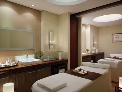 Eleganter Spa-Raum mit zwei Massageliegen, ruhiger Beleuchtung und stilvoller Holzdeko.