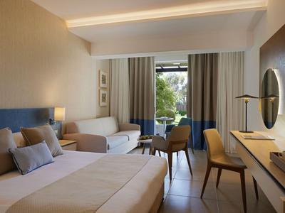 Modernes Hotelzimmer mit Doppelbett, Sitzbereich und Balkon mit Ausblick ins Grüne.