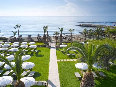 View of a hotel garden with sun loungers and umbrellas near the sea.