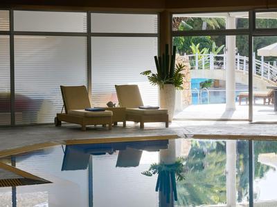 Innenpoolbereich mit Liegestühlen und Sicht auf Außenpool und Garten