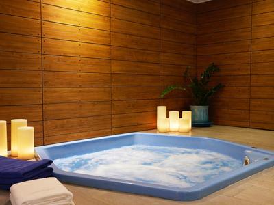 Entspannender Whirlpool in einem Raum mit Holzverkleidung und Kerzenlicht.