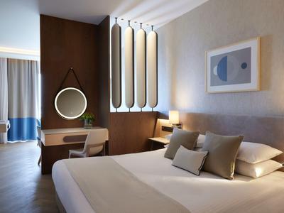 Modernes Hotelzimmer mit großem Bett, Schreibtisch und stilvoller Beleuchtung.