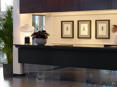 Elegante Hotellobby mit Empfangstresen, Pflanzen und moderner Dekoration in warmen Tönen