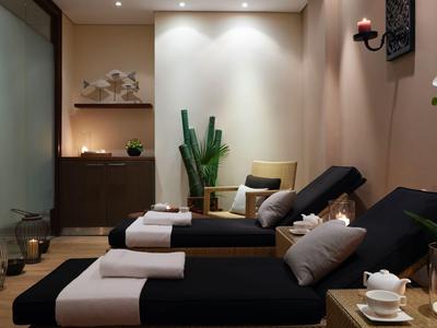 Ein gemütlicher Wellnessraum mit Liegen, Kissen und entspannter Beleuchtung.