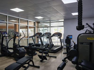 Moderner Fitnessraum mit Laufbändern, Crosstrainern und Kraftgeräten in einem Hotel.