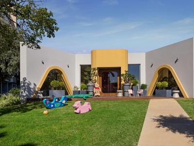 Modernes Hotel mit bunter Kinderspielzeugwiese und klarem Himmel.