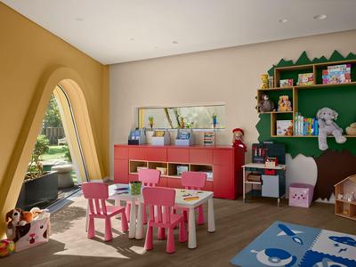 Kinderspielecke mit bunten Möbeln, Spielzeug und einer großen Fensterbogenform in einem hellen Raum.