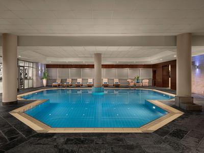 Moderner Indoor-Pool mit sechseckigem Becken und bequemen Liegestühlen im Hotelbereich.