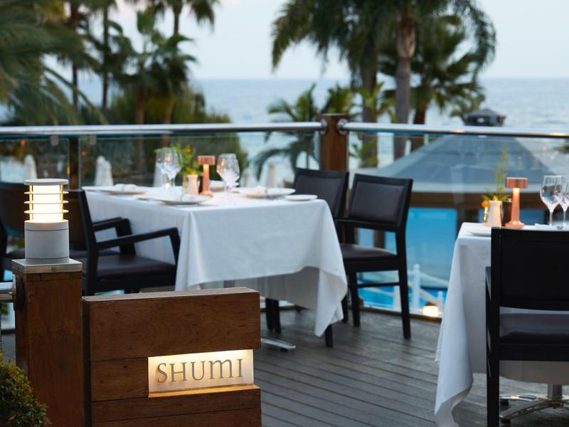 Elegant restaurant with set tables and sea view on a terrace.