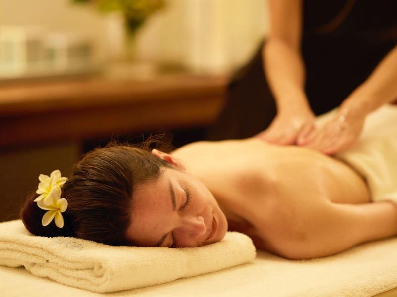 Woman relaxes during a back massage in a spa with warm lighting.