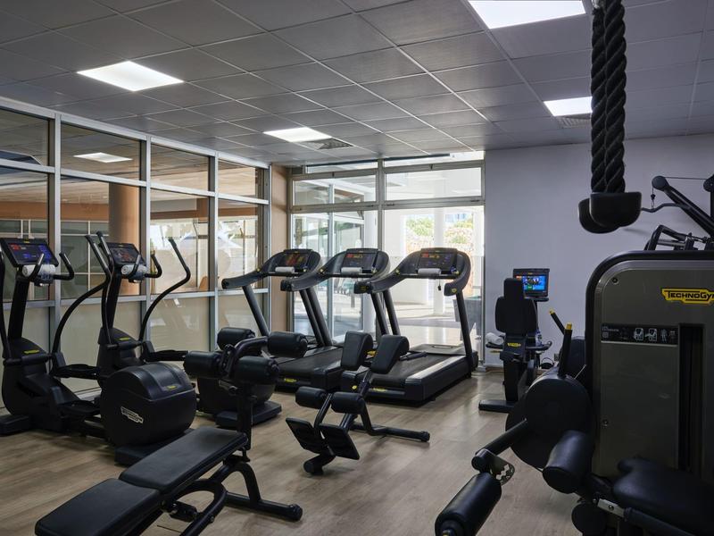 Modern gym with treadmills, bikes, and strength machines in a bright room.